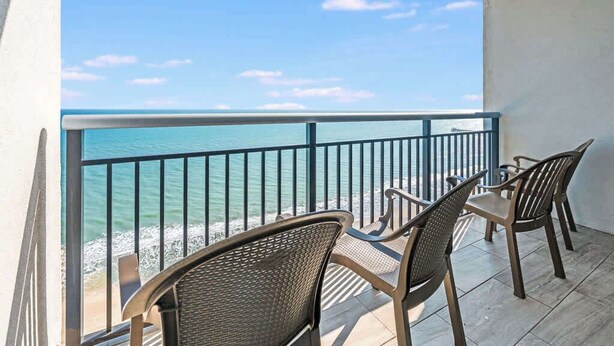A balcony with a view of the ocean, equipped with four chairs and a table. - Amaze 18th floor Direct Ocean front Views & Pools (Myrtle Beach)