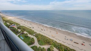 Una playa con una vista despejada del océano, una orilla arenosa y algunas sombrillas.