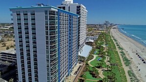 Un hotel de gran altura con múltiples pisos, ubicación frente a la playa y vista al océano.