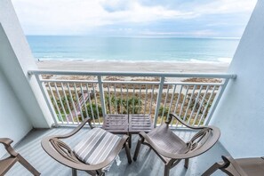 A balcony with two chairs and a table, overlooking a beach with a clear view of the ocean. - Amazing Direct Oceanfront Views - Luxurious Suite! (Myrtle Beach)