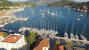 Ein Yachthafen mit zahlreichen Segelbooten, umgeben von Gebäuden und Hügeln.