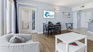 Ein modernes Wohnzimmer mit einer Couch, einem Esstisch und einem Fernseher, der 'BIG FISH RENTALS' anzeigt.