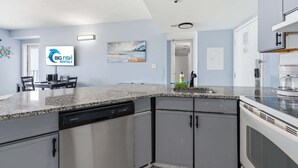 Eine moderne Küche mit Granit Arbeitsplatten, einem Geschirrspüler und grauen Schränken.