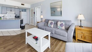 Ein Wohnzimmer mit grauem Sofa, weißem Couchtisch und einem Holznachttisch.