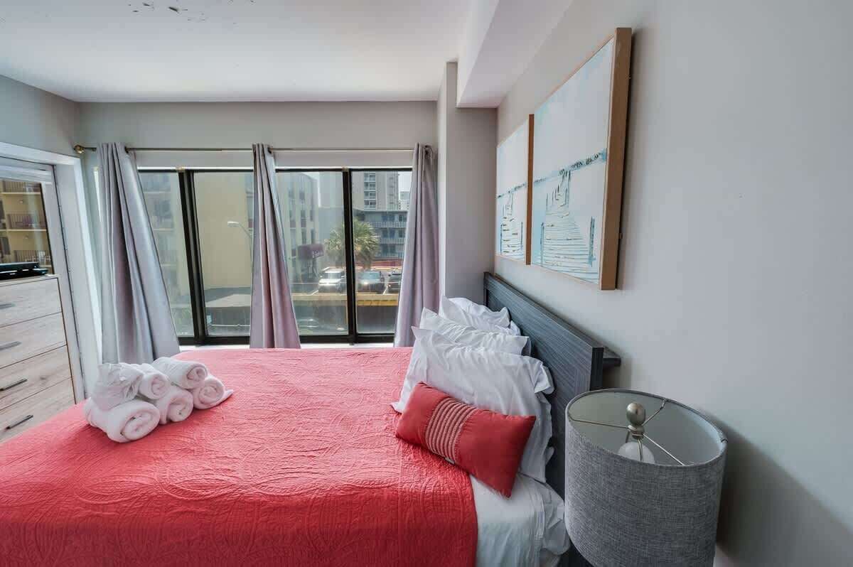 A hotel room with a large bed, a nightstand, a lamp, and a window with curtains.