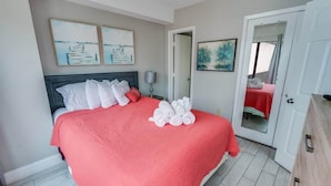 A neatly made bed with white and red linens, a bedside lamp, and artwork on the walls. - Palace Resort 2BR, Pools & Ocean Views, 2nd Floor (Myrtle Beach)
