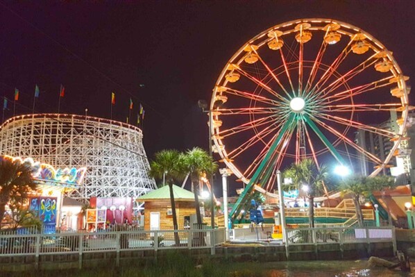 Una noria y una montaña rusa en un parque de atracciones nocturno.