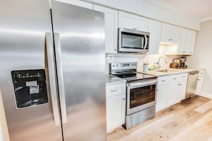 Een moderne keuken met roestvrijstalen apparatuur, witte kasten en een ingebouwde waterdispenser.