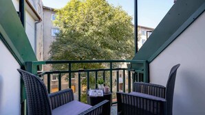 A balcony with wicker furniture, a small table, and a potted plant.