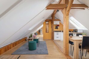 Un loft moderno con techo inclinado, vigas de madera, una zona de cocina y un espacio para comer.