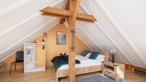 A cozy attic bedroom with a wooden bed frame, a white wardrobe, and a small desk. - Air-conditioned apartment in Kazimierz | Parking | Workplace (Kraków)