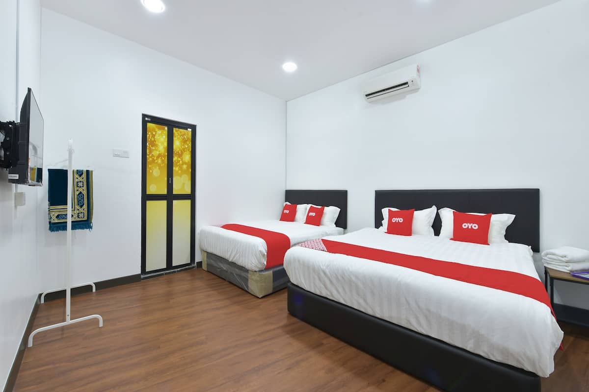 Habitación de hotel con dos camas, ropa de cama blanca, almohadas rojas, suelo de madera y un equipo de aire acondicionado.
