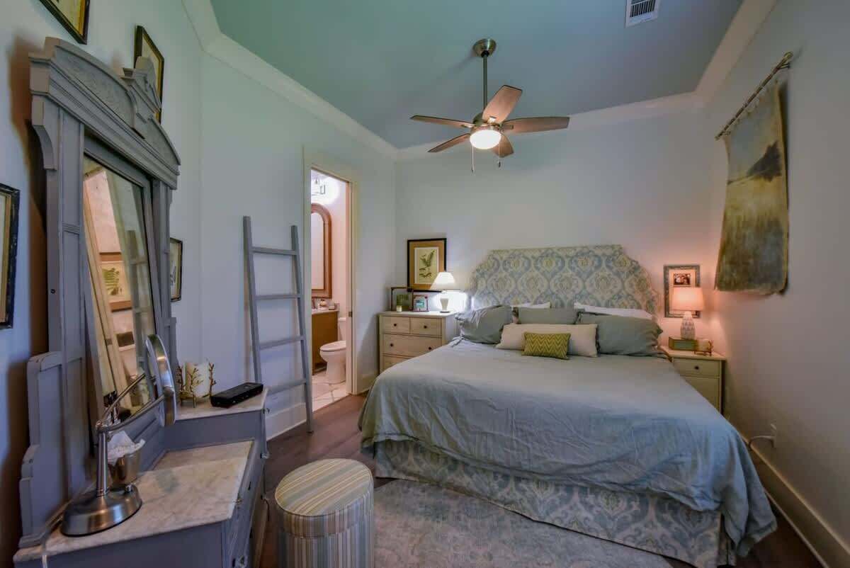 A bedroom with a bed, bedside tables, a ceiling fan, and a mirror.