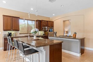 A modern kitchen with a central island, bar stools, and built-in appliances.