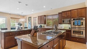 Una cocina amplia con armarios de madera oscura, una isla central con estufa y un ventanal que proporciona luz natural.