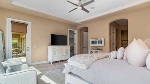 Un dormitorio con cama, televisión, cómoda y ventilador de techo.