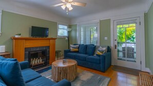 A living room with a fireplace, a blue sofa, a round coffee table, and a television on a stand. - North Park Haven Summ (San Diego)