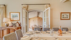 Comedor con una mesa dispuesta para cuatro, incluyendo copas de vino, platos y cubiertos.