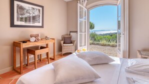 Un dormitorio con cama, escritorio, silla y vistas al mar.