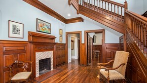 A spacious room with a wooden staircase, a fireplace, and two antique chairs. - King Suite in Boutique Inn (Winston-Salem)