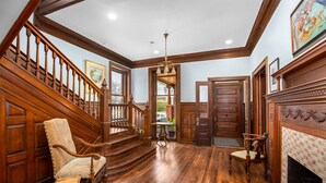 A spacious foyer with a wooden staircase, a fireplace, and a large window. - King Suite in Boutique Inn (Winston-Salem)