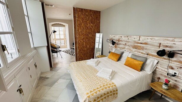 Um quarto com cama, mesas de cabeceira, guarda-roupa e espelho.