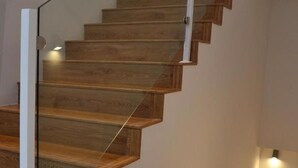 Eine moderne Treppe mit Holzstufen und Glastrennwand.