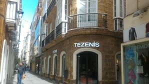 A building with the sign "TEZENIS" on the facade, featuring arched windows and a balcony with a wrought iron railing. - Apto. 1 Dorm. Ext. 2ª Planta (Cádiz)