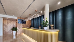 Una moderna recepción con un diseño elegante, una planta en maceta grande y una lámpara decorativa.