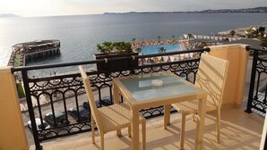 Balcón con mobiliario de mimbre que da a una piscina y al mar.