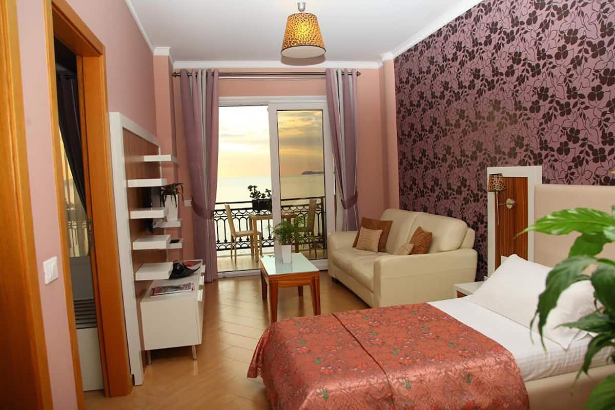 A hotel room with a balcony, a sofa, a bed, and a small table.