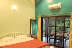 A room with a bed, a bedside table, a window with curtains, and an air conditioning unit.