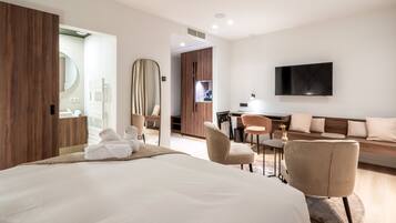 Quarto de hotel moderno com uma cama grande, uma escrivaninha, uma televisão e um sofá.