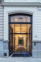A grand entrance with a black door and glass panels, leading into a well-lit hallway.