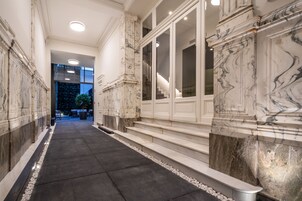 A marble-lined corridor with steps leading to a staircase.