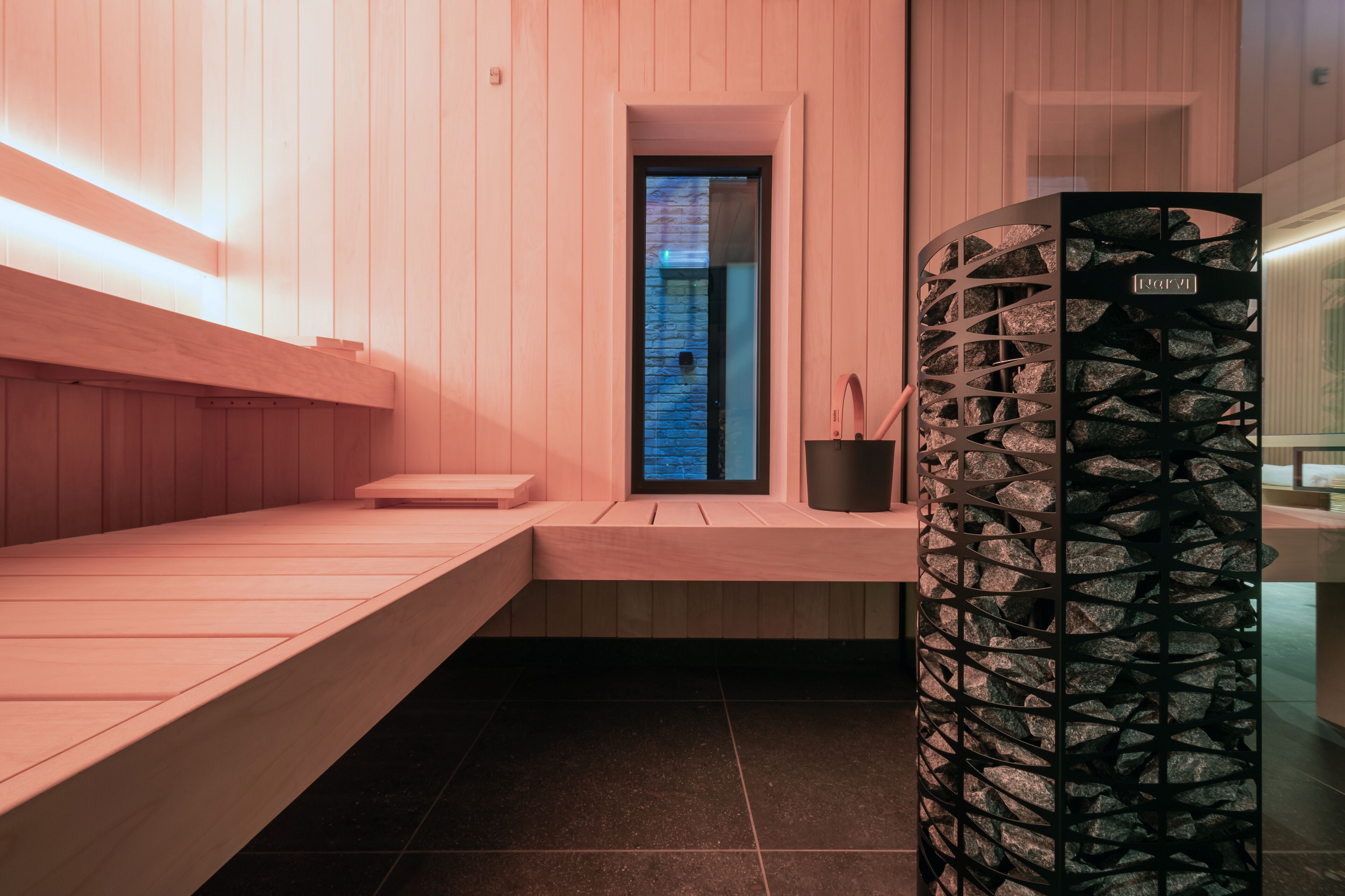 Una sauna moderna con bancos de madera y una pared de piedra.