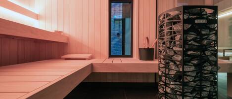 Una sauna moderna con bancos de madera y una pared de piedra.