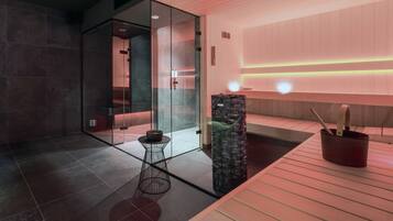 Un baño moderno con cabina de ducha de vidrio, una pequeña mesa redonda y un pilar de piedra.