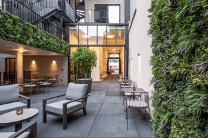 An outdoor seating area with tables and chairs, a staircase, and a vertical garden wall.