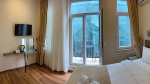 A hotel room with a bed, a desk with a coffee maker, a TV, and a balcony with outdoor seating. - Taksim Nacre 360 Suit (Istanbul)