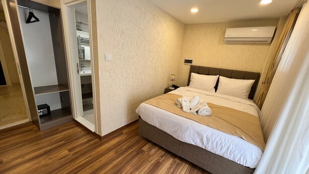 A hotel room with a bed, a wardrobe, a bathroom, and an air conditioning unit. - Taksim Nacre 360 Suit (Istanbul)