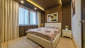 Ein Schlafzimmer mit einem großen Bett, einem Nachttisch, einem Spiegel und einem Fenster mit Vorhängen.
