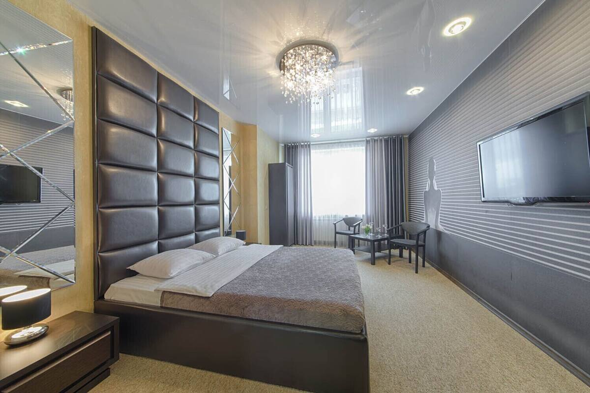Une chambre d’hôtel moderne avec un grand lit, un bureau et un téléviseur fixé au mur.
