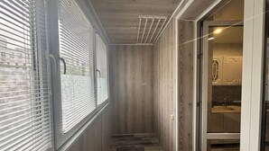 Ein schmaler Korridor mit Holzwänden und Fliesenboden, der zu einem Badezimmer mit Waschbecken und Schränken führt.