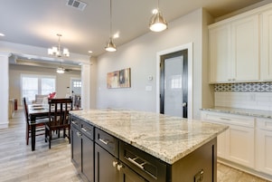 A modern kitchen with granite countertops, white cabinetry, and pendant lighting.