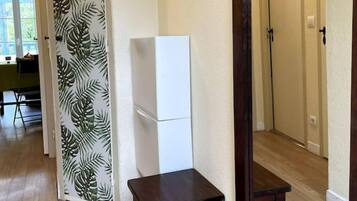 Un corridoio con pavimento in legno, un piccolo tavolo scuro in legno e un armadietto bianco.