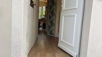 A hallway with a wooden floor leading to a room with a patterned door.