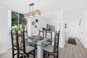 A modern kitchen with white cabinets, a glass dining table, and a hanging light fixture. - Harbor Cottage North Coast Village G36-Ocean Views-*Super Close To Beach* (Oceanside)