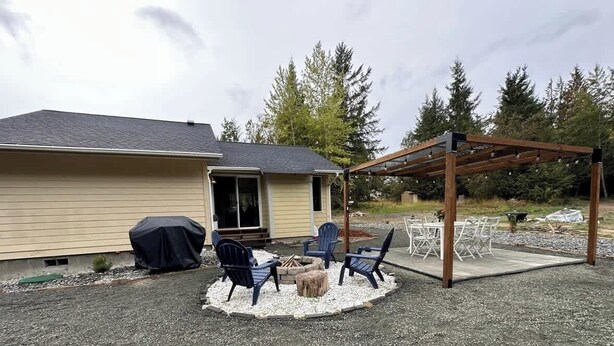Ein überdachter Patio-Bereich mit Außenmöbeln und einem Feuerkorb.