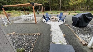 Eine Außenpatio mit Pergola, Sitzgruppe und Feuerstelle.
